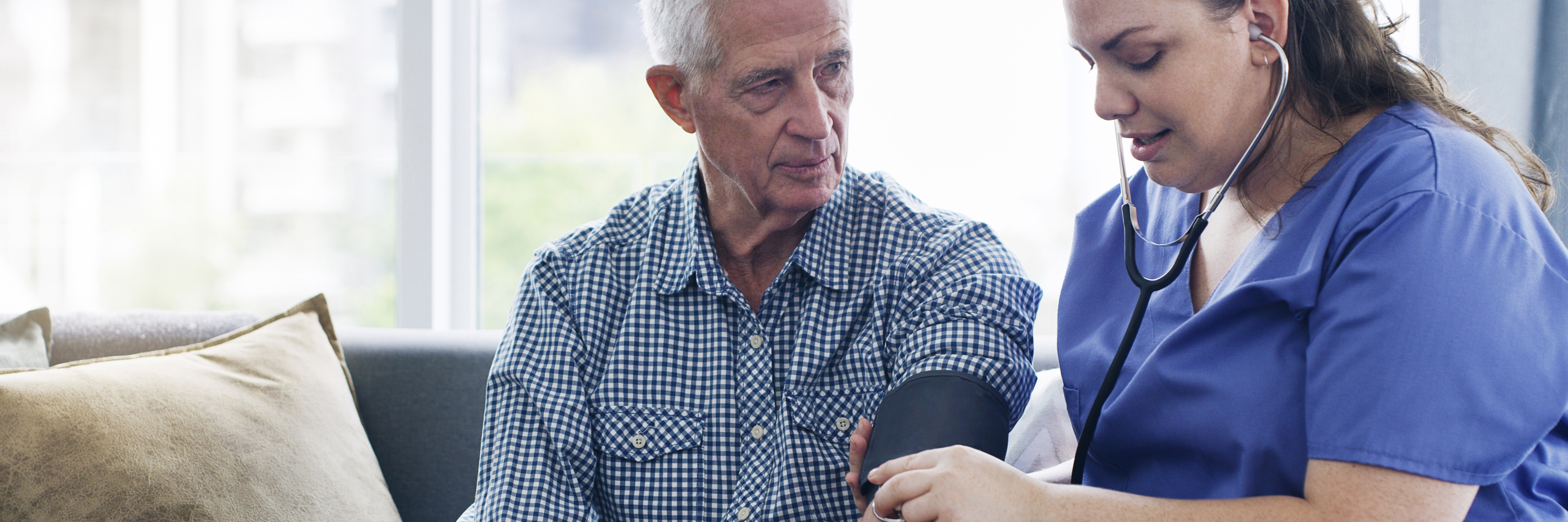 Female nurse taking an older man's blood pressure