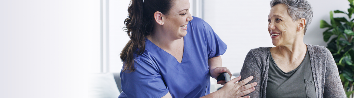 Nurse smiling at older woman seated in wheelchair