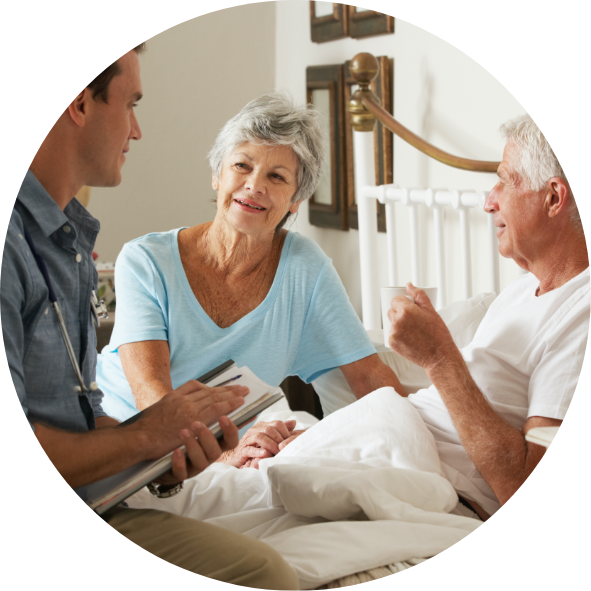 Healthcare professional talking to an elderly couple in a bedroom.